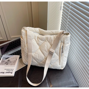 Detail of quilted puffer tote bag with adjustable strap and side zipper pocket