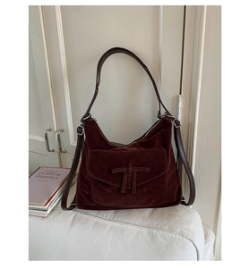 Close-up of retro deep burgundy suede shoulder bag featuring a unique T-bar knot buckle detail