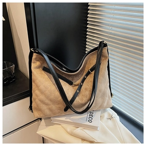 Detail of quilted khaki suede tote with black leather trim and gold metal hardware