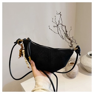 Detail of black suede crescent bag with stitching texture and wooden bead charm