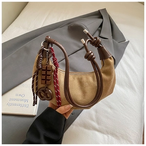 Détail du sac croissant en daim kaki avec nœud en cuir marron et breloque chocolat