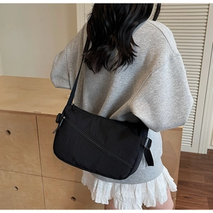 Rear view of model wearing a black nylon crossbody bag with adjustable shoulder strap