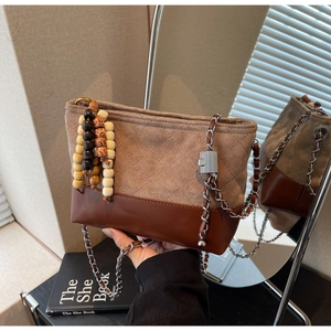 Detail of vintage quilted suede and leather bucket bag with wooden bead charm
