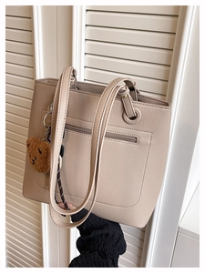 Beige pebble leather tote bag featuring a rear zipper pocket and a brown bear charm