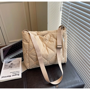 Detail of light beige quilted tote bag with rhombus stitching on a leather seat