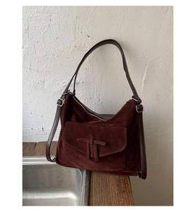 Detail of burgundy suede tote bag featuring a decorative bow and silver metal buckle