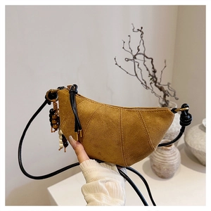 Close-up of brown suede crescent bag with thin shoulder strap and wooden bead charm