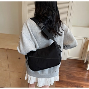 Detailed back view of a black nylon crescent crossbody bag worn by a model in casual setting
