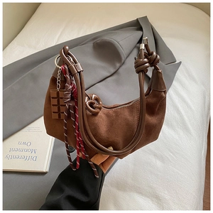 Détail du sac hobo en daim marron avec poignée nouée et breloque en chocolat