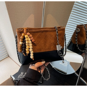 Detail of vintage matte crossbody bag with quilted stitching and beaded tassel charm