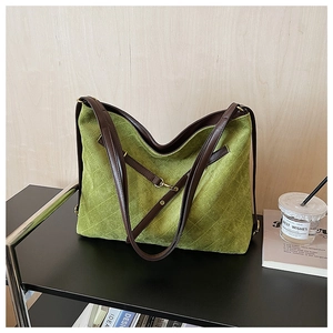 Detail of green quilted tote bag with brown leather straps and gold metal buckles
