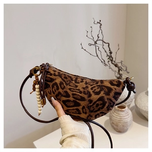 Detail of leopard print crescent bag with brown leather strap and decorative beads