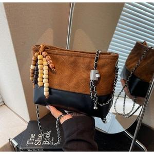 Detail of vintage quilted bucket bag with suede texture and wooden bead pendant