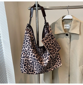 Detail of leopard print tote bag set featuring leather handles and matching pouch