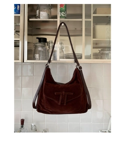 Detail of dark brown suede hobo bag featuring a decorative bow and adjustable leather strap