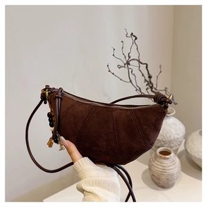 Detail of dark brown suede crescent bag with wooden bead and metal pendant decor