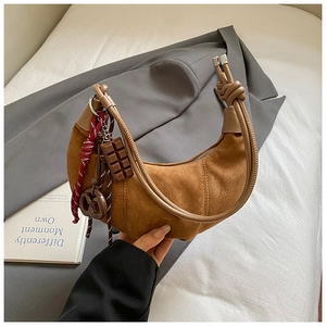 Détail du sac croissant en daim avec breloques bretzel et chocolat et bandoulière nouée