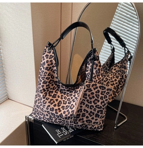 Detail view of leopard print hobo bag set with matching small zipper pouch on a wooden table