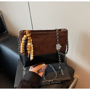 Detail of frosted brown suede bucket bag with diamond stitching and bead tassel charm