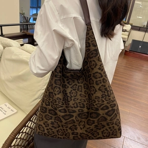 Gros plan du sac seau en daim imprimé léopard avec bandoulière en cuir brun