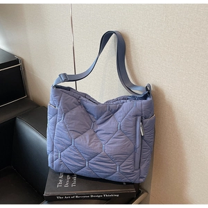 Detail of blue quilted nylon tote bag featuring adjustable shoulder strap and padded texture