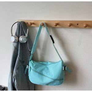 Detail view of mint green nylon crossbody bag with zipper pocket and adjustable strap