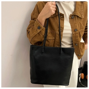 Detail view of large black tote bag in matte faux leather with slim dual shoulder straps