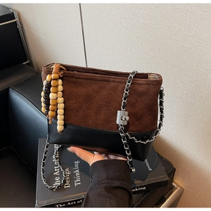 Detail of vintage quilted brown suede and black leather bucket bag with silver chain
