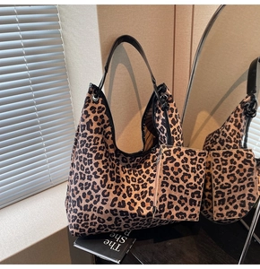 Close-up of leopard print tote bag with black leather straps and matching mini pouch