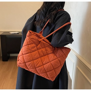 Modèle portant un grand cabas orange avec surpiqûres en losange et design matelassé