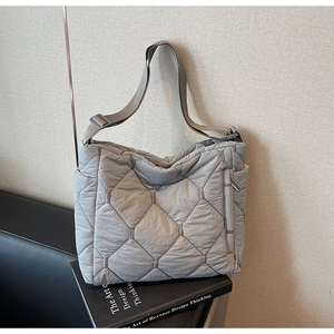 Detail showing the gray quilted texture and side zipper on this padded shoulder bag