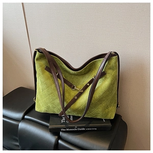 Detail of green quilted suede shoulder bag with brown leather strap on books