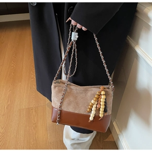 Detail of vintage quilted bucket bag with brown leather contrast and wood bead charm