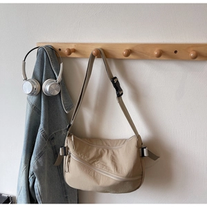 Detail of adjustable strap and buckle on a beige waterproof nylon crescent shoulder bag