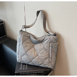 Detail of grey quilted nylon tote bag featuring diamond patterns and adjustable strap