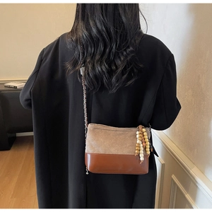 Close-up of quilted fabric crossbody bag with wooden bead fringe and chain strap