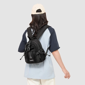 Detail of a black mini nylon backpack showing buckle straps and mesh side pockets