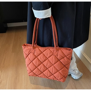 Détail du grand sac cabas matelassé orange sur mannequin montrant taille et texture