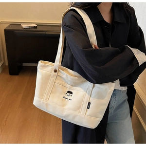 Detail einer bestickten Canvas-Tasche mit süßem Motiv und Docile girl Schriftzug
