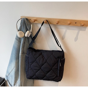 Detail of black puffer tote bag side pocket with silver zipper on a wooden wall hook