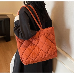 Modèle portant un grand sac cabas matelassé orange dans un cadre intérieur minimaliste
