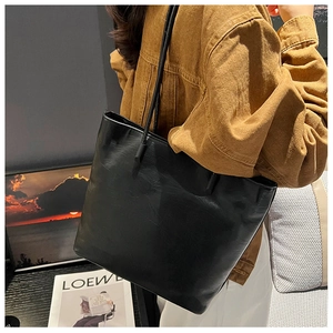 Close-up of black leather tote bag with natural grain texture and sturdy shoulder straps