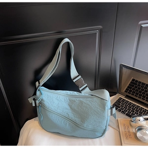 Close-up of light blue nylon crossbody bag with pleated texture and adjustable strap