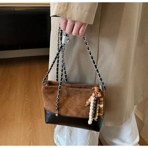 Brown suede bucket bag with quilted patterns and wooden bead tassel in a lifestyle setting