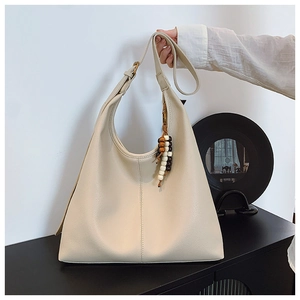 Detail of off-white tote bag featuring lychee grain texture and beaded shoulder strap