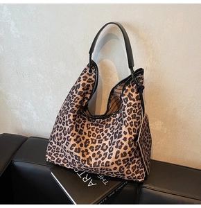 Macro detail of large leopard print tote bag with black leather straps and mini pouch