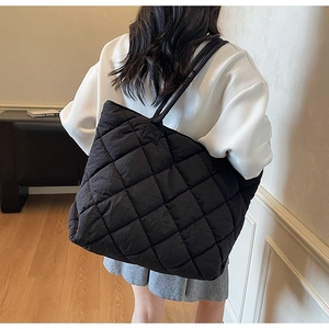 Vue détaillée d'un grand sac cabas noir matelassé porté à l'épaule par un mannequin
