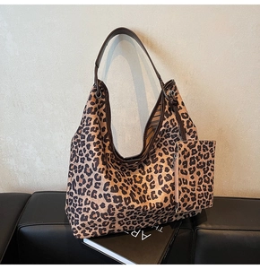 Detailed view of leopard print tote bag with a small matching pouch on a leather bench