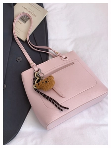 Detailed macro view of pink litchi grain tote bag featuring a cute brown plush bear charm
