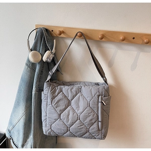 Detail of grey quilted puffer tote bag showing the side zipper pocket and adjustable strap